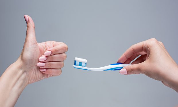 Toothbrush in woman's hands on gray background