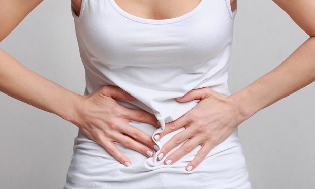 Woman with stomachache, having food poisoning or menstrual period cramp over grey background