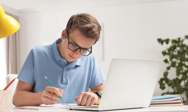 Teenager boy doing his homework at desk indoors