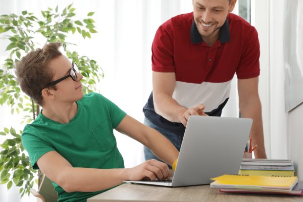 Father helping his teenager son with homework indoors