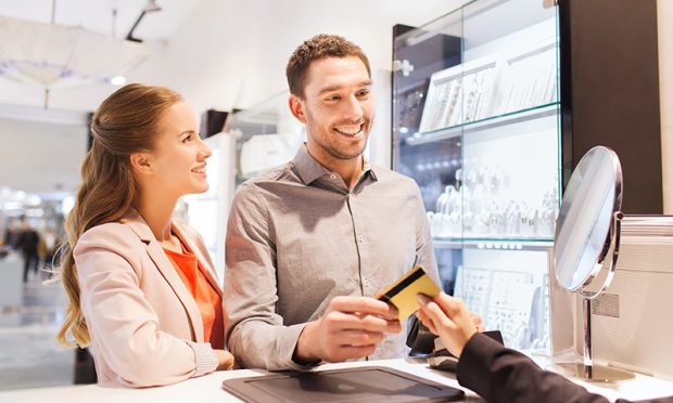 sale, consumerism, shopping and people concept - happy couple with credit card at jewelry store in mall